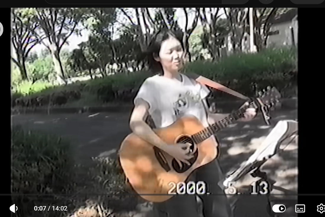 2000年5月13日、屋外でギターを弾くRIEKOの作中映像